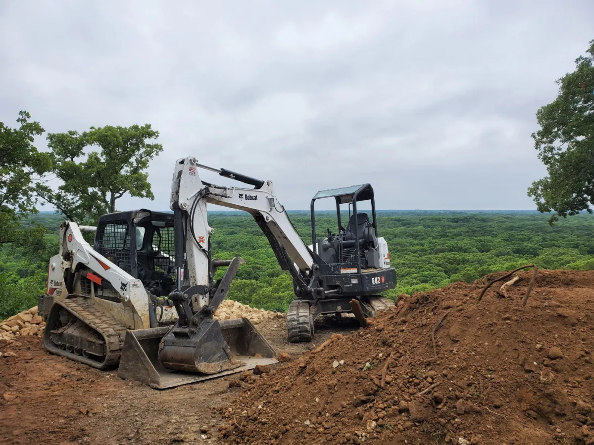 Our featured contractor's track loader and mini excavator on a cleared hilltop site