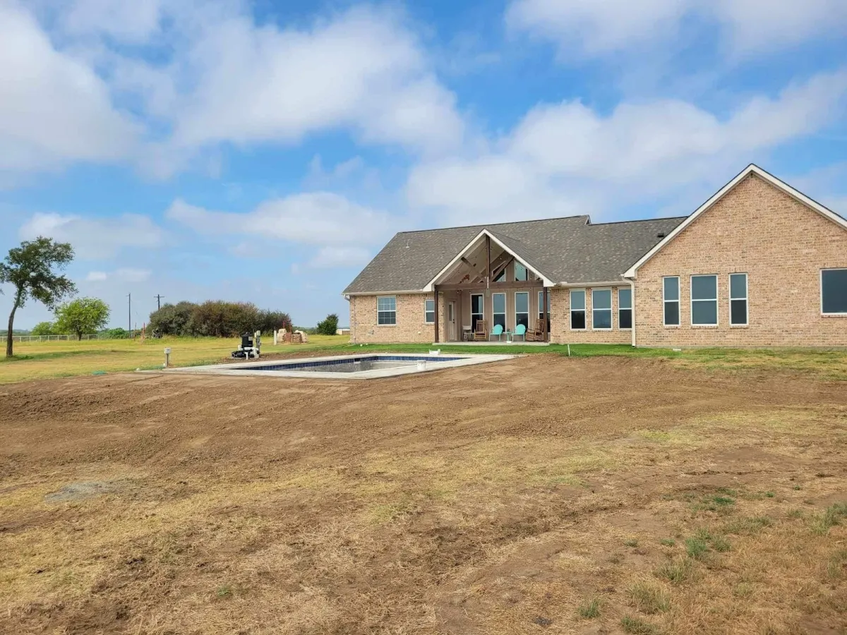 A freshly graded yard behind a new brick home on acreage